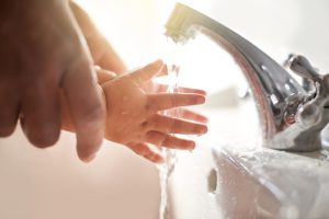 Closeup shot of a father helping his baby girl wash her hands at a tap